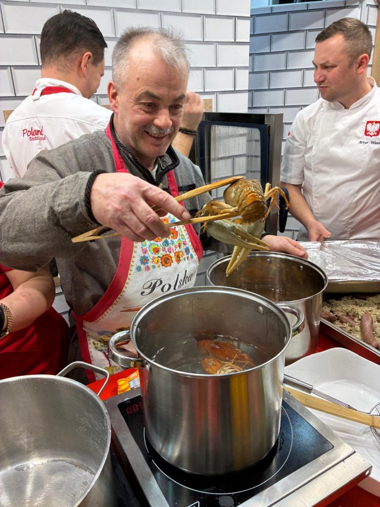 Przewodniczący zwycięskiego Koła Gospodyń Wiejskich  Zakocie „Wygodni Zakociacy” podczas robienia zwycięskiej potrawy : Raki po polsku – derte koty na targach Grüne Woche w Belinie.